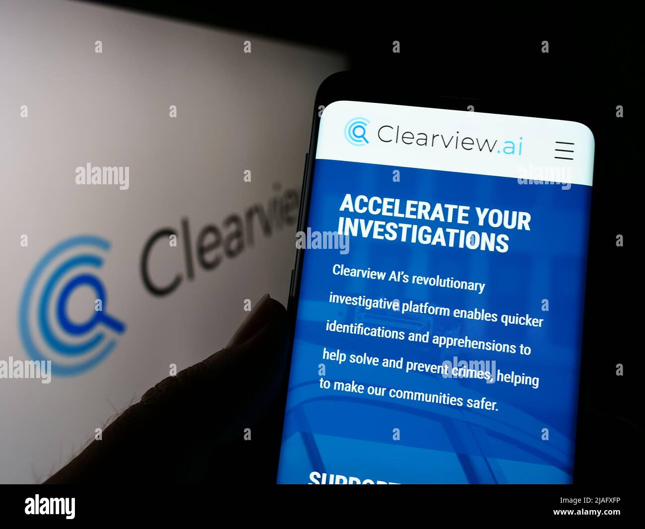 Person holding smartphone with webpage of facial recognition company Clearview AI Inc. on screen with logo. Focus on center of phone display. Stock Photo