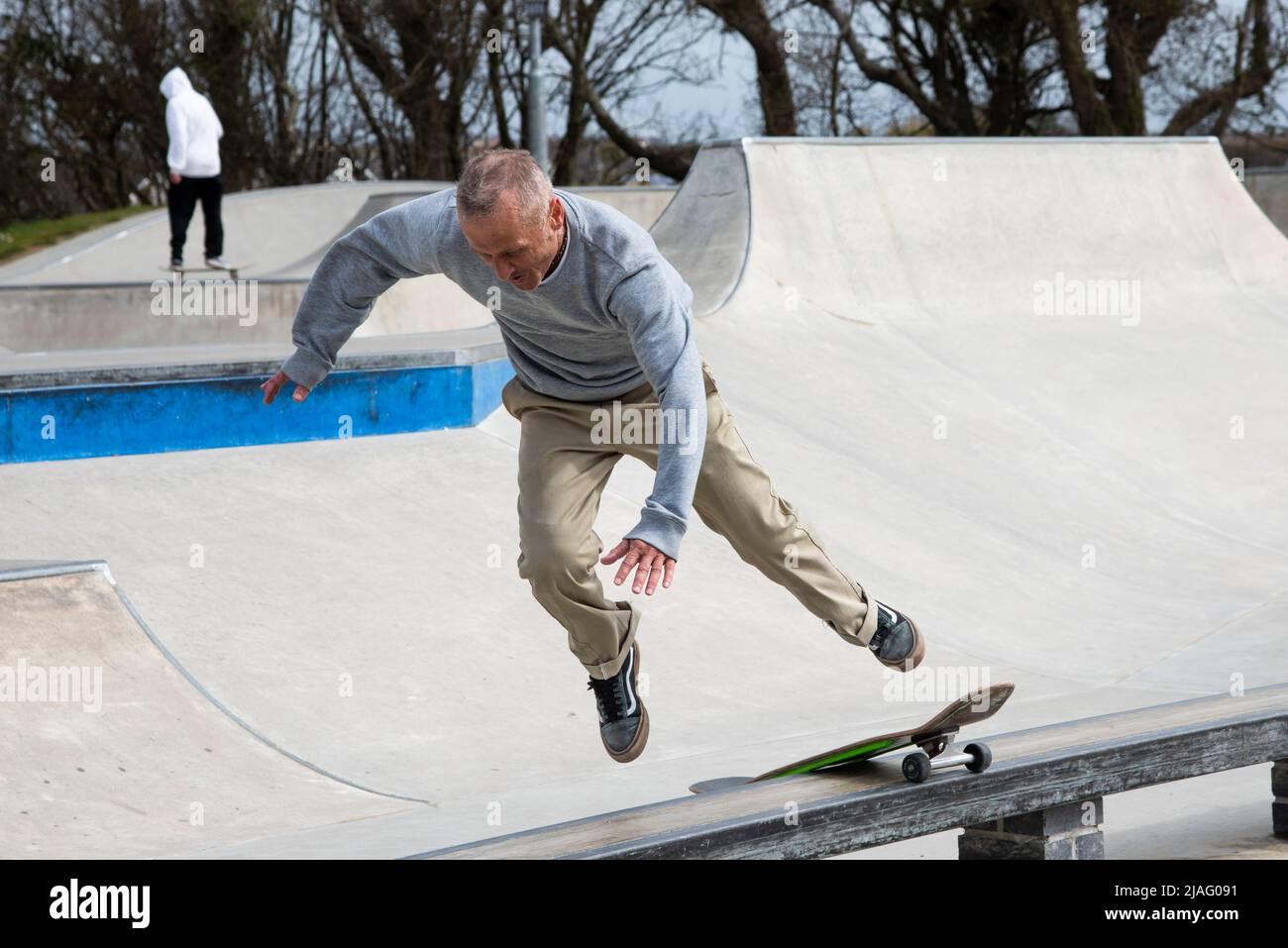 A mature male skateboarder attempting to perform a boardslide railslide trick and failing at Newquay Concrete Waves Skatepark in Newquay in Cornwall i Stock Photo