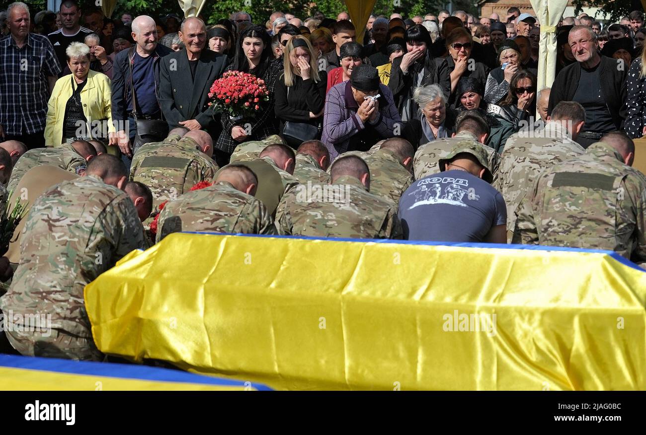 VINNYTSIA, UKRAINE - MAY 29, 2022 - Soldiers kneel near the coffins with the bodies of nine KORD servicemen who perished in a Russian missile attack i Stock Photo