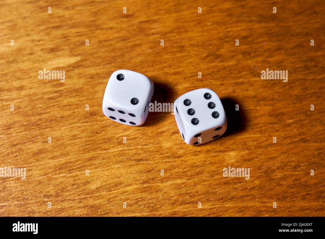 Two white dice on a wooden table Stock Photo