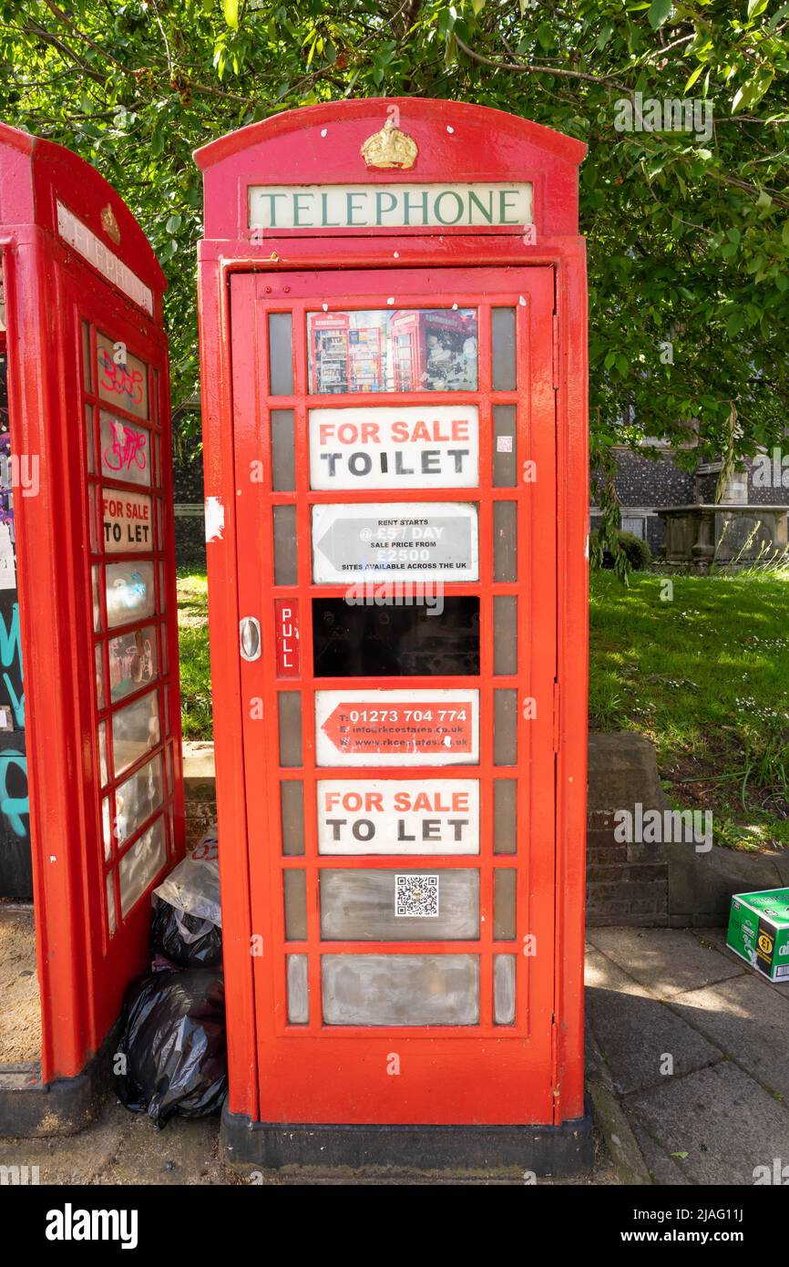 Traditional red telephone box being used with signs on glass stating