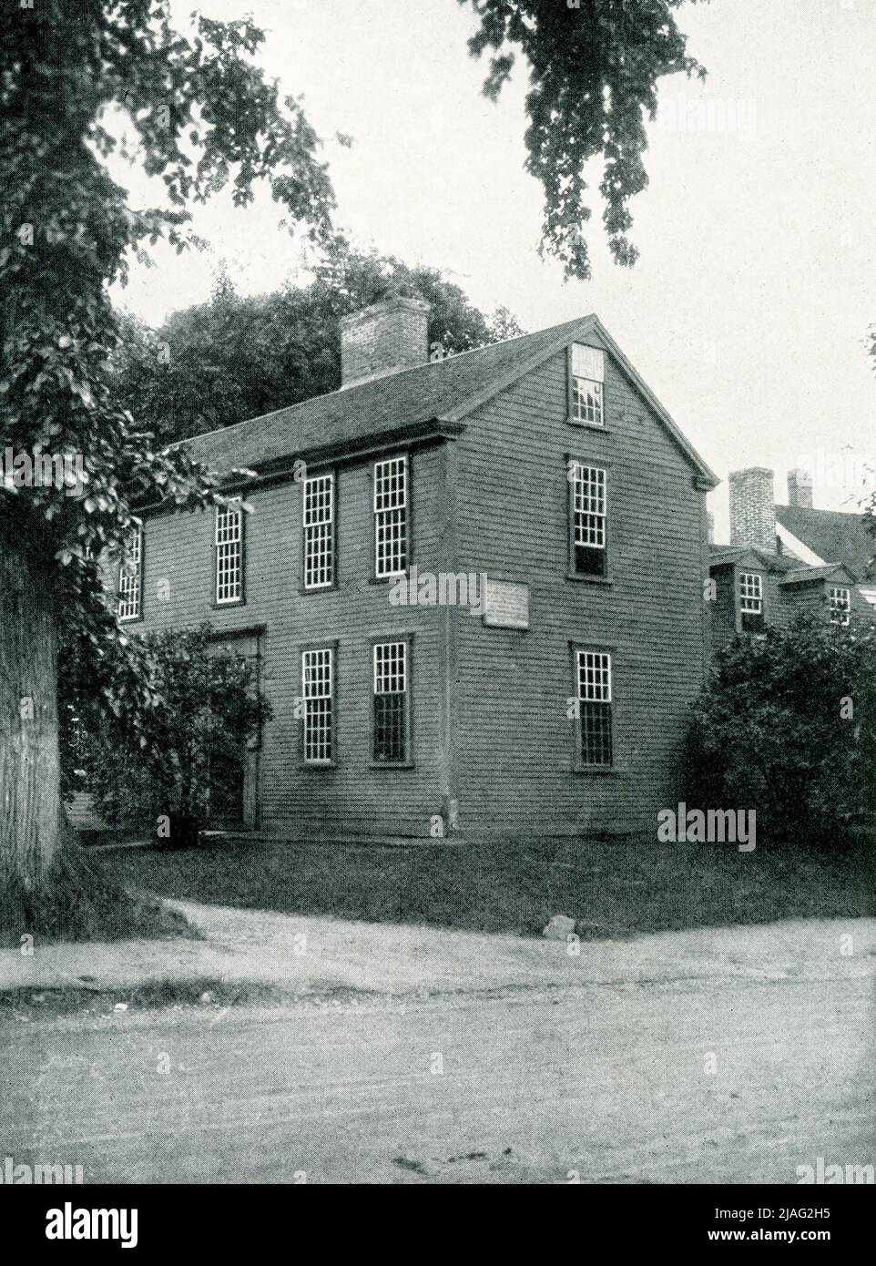 The 1920 caption reads: “Lexington, Massachusetts—the house in which Samuel Adams and John Hancock were asleep when roused by Paul Revere.” The Hancock-Clark House in Lexington, Massachusetts, is where John Hancock and Samuel Adams were awakened by Paul Revere on April 18, 1775. The men were asleep in “the parlor” of the house built in 1737 by Thomas Hancock for his father Rev. John Hancock. Stock Photo