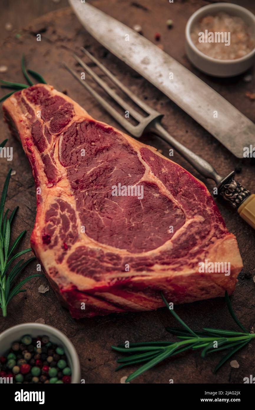 uncooked bloody meat with vintage cutlery, rosemary and little bowls of