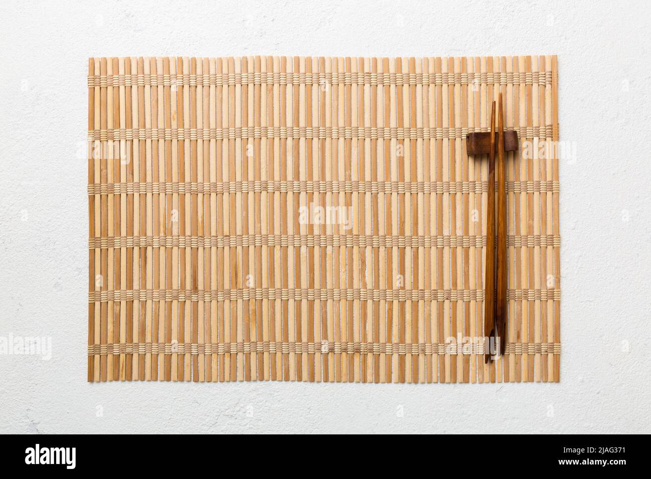 Two chopsticks and bamboo mat on cement background. Top view copy