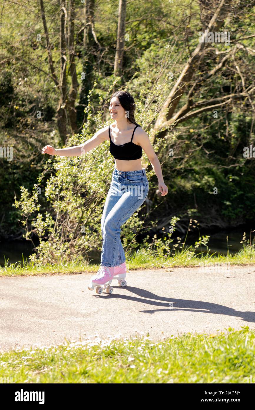 brunette woman skating in the park with pink roller skates Stock Photo