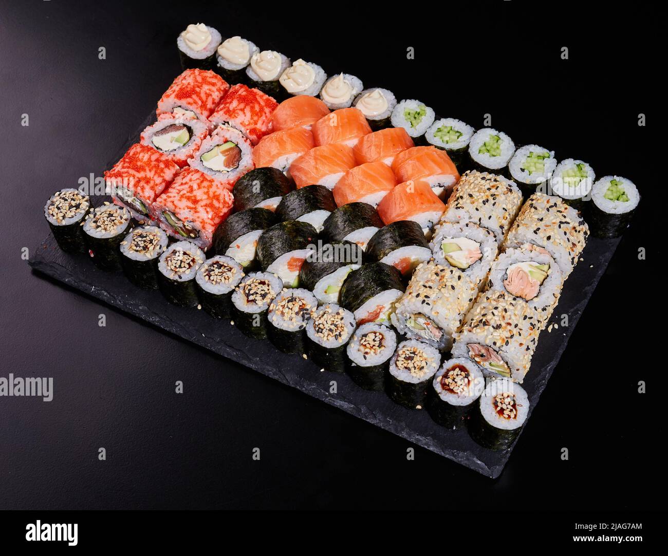 https://c8.alamy.com/comp/2JAG7AM/large-set-of-various-sushi-rolls-with-fresh-different-fillings-on-a-black-stone-plate-2JAG7AM.jpg