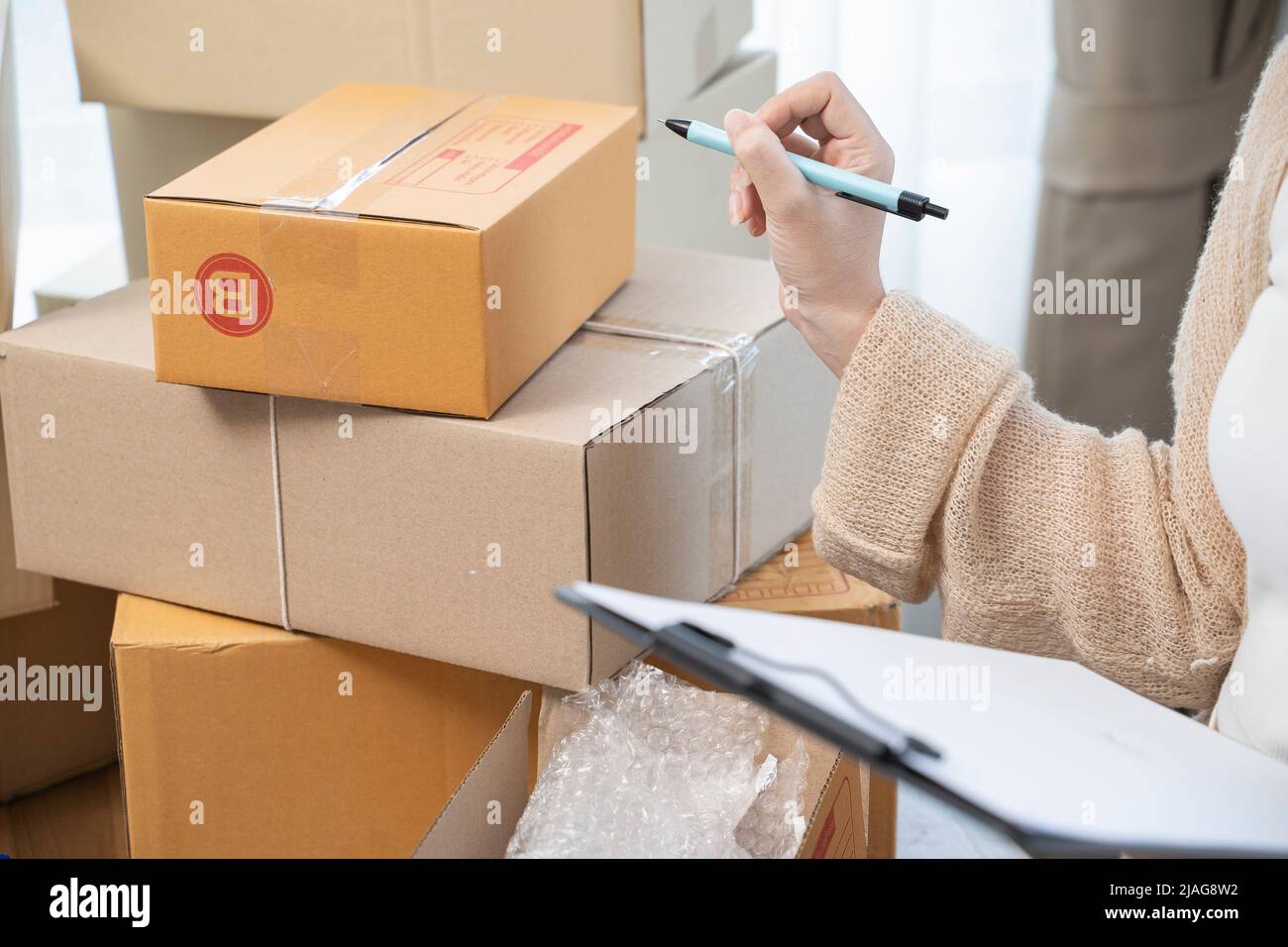 Asian woman packing in boxes to work at home Small Business Owners or Startup Small Business Entrepreneurs working on online marketing shipping boxes. Stock Photo
