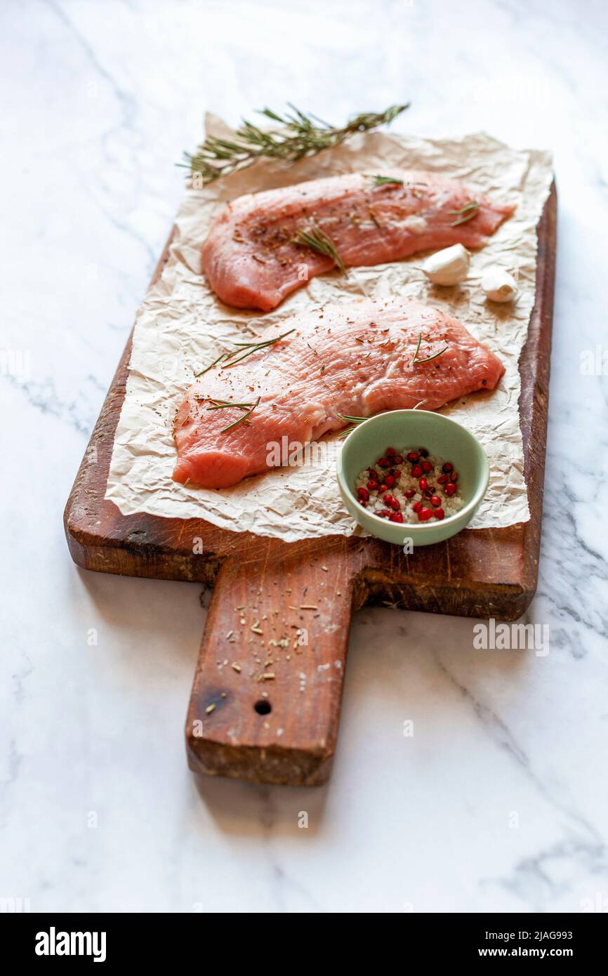 Two raw veal escalope on the old wooden cutting board Stock Photo