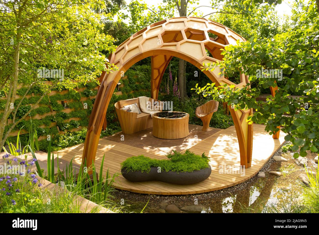 A dome shaped pavilion over a decked seating area in a woodland setting in The Meta Garden: Growing the Future designed by Joe Perkins Stock Photo