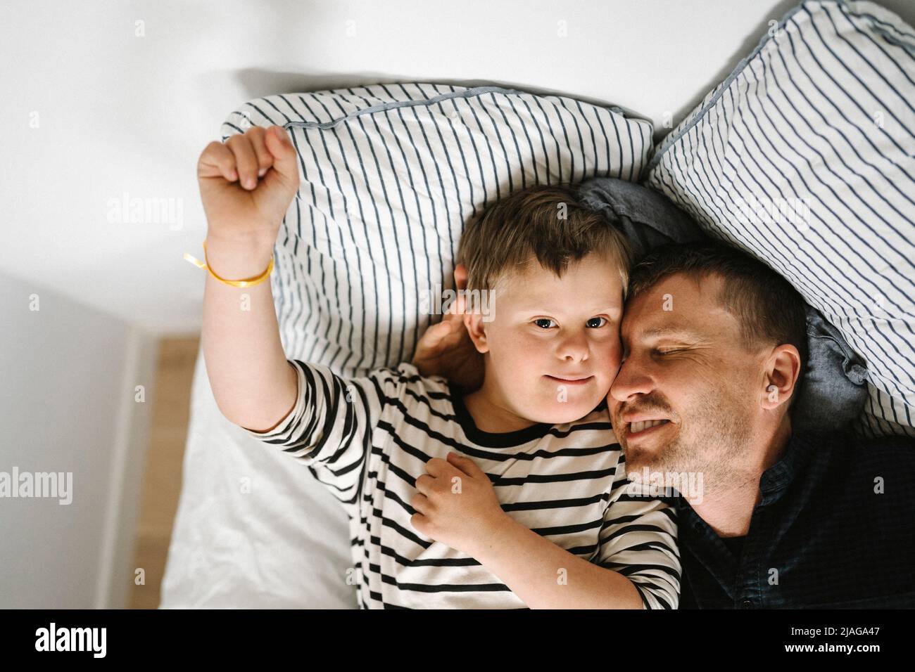 Directly above shot of father and son resting on bed in bedroom Stock Photo