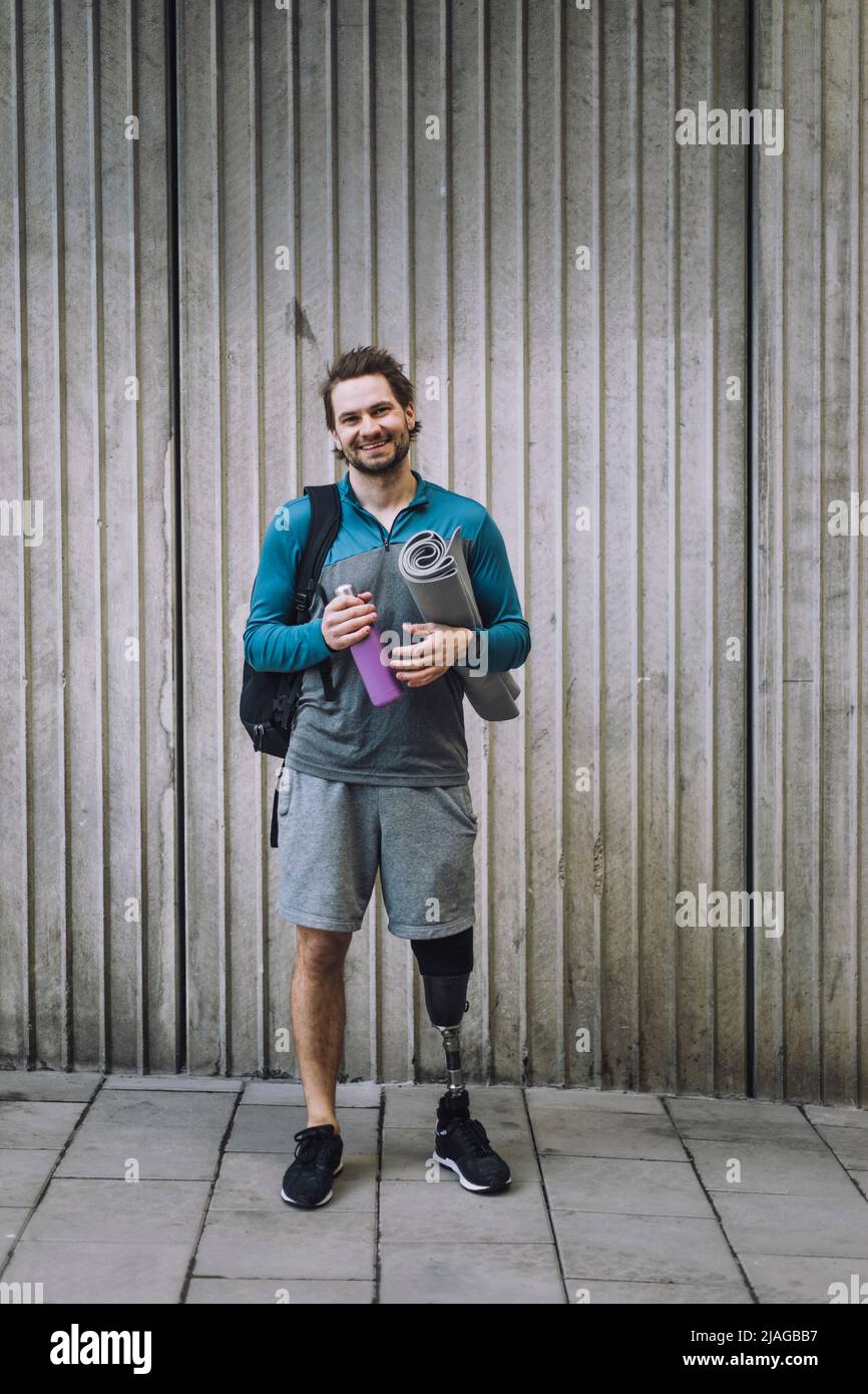 https://c8.alamy.com/comp/2JAGBB7/full-length-portrait-of-man-with-disability-carrying-exercise-mat-and-water-bottle-in-front-of-wall-2JAGBB7.jpg