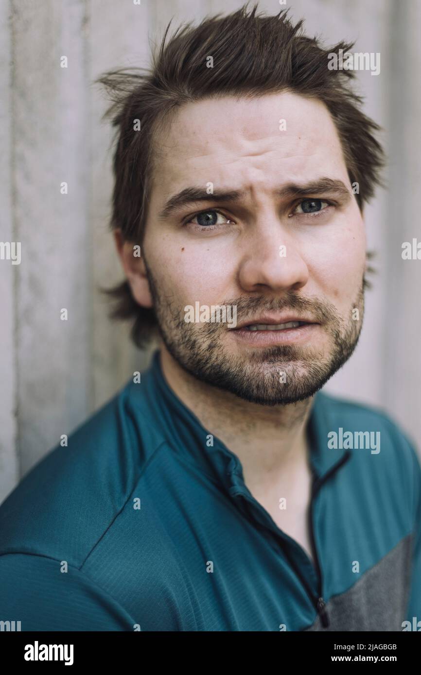 Portrait of young man standing against wall Stock Photo - Alamy