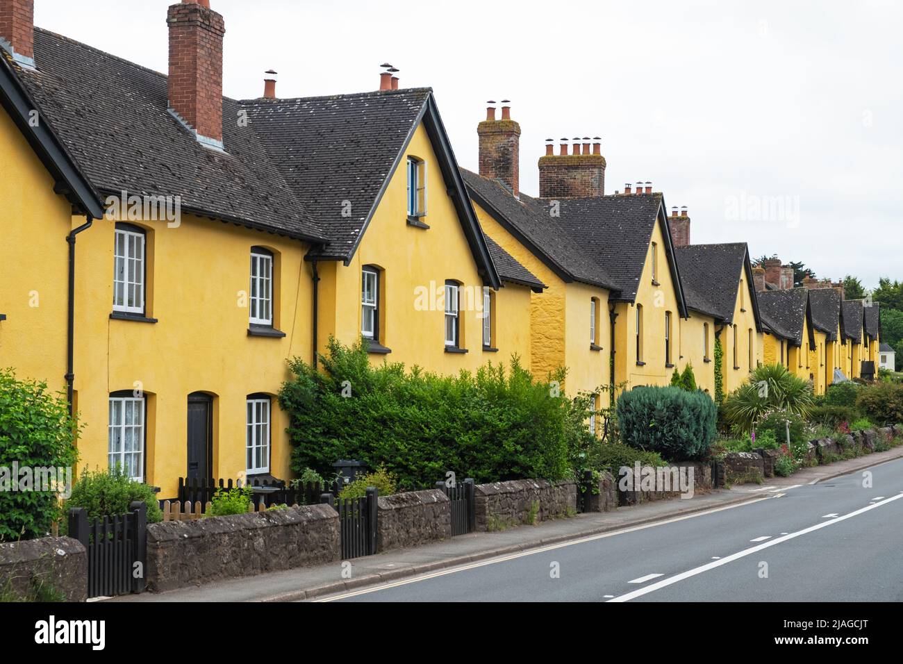 Row of vividly painted cottages lining a village roadside in East Devon, UK Stock Photo