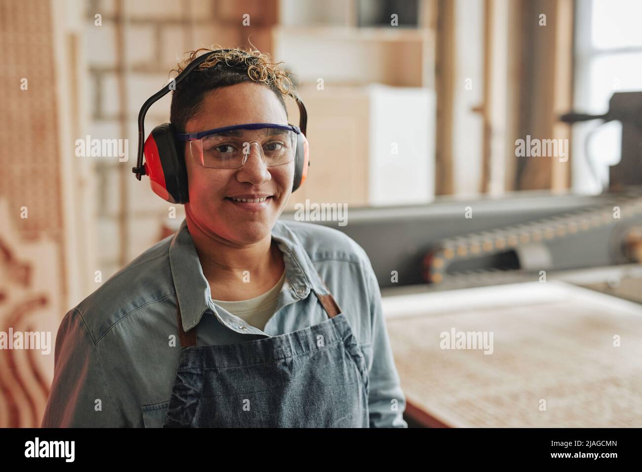 Portrait of female worker smiling at camera while wearing noise ...