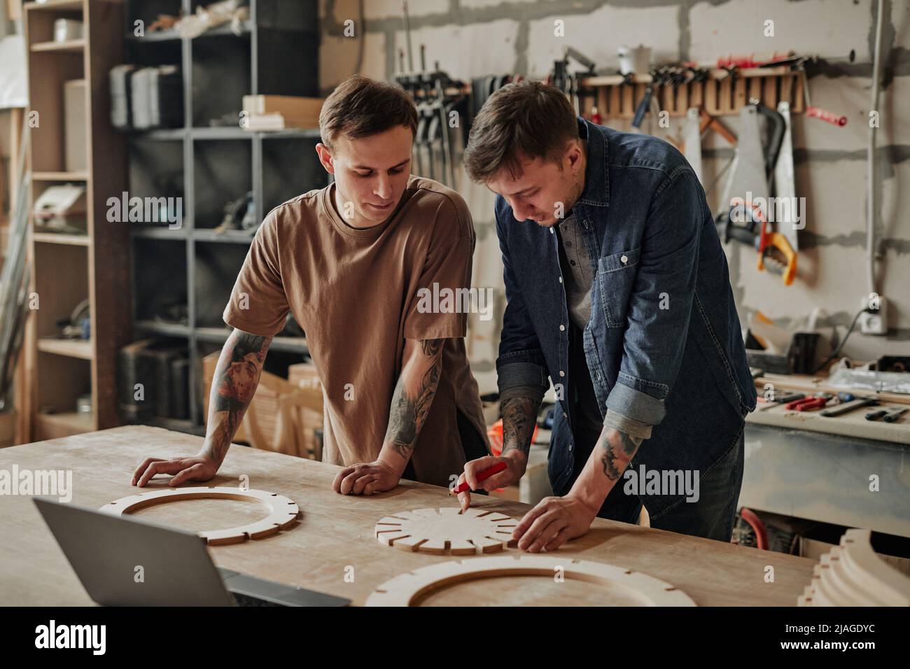 Portrait of two artisan shop owners designing wooden furniture in workshop interior Stock Photo