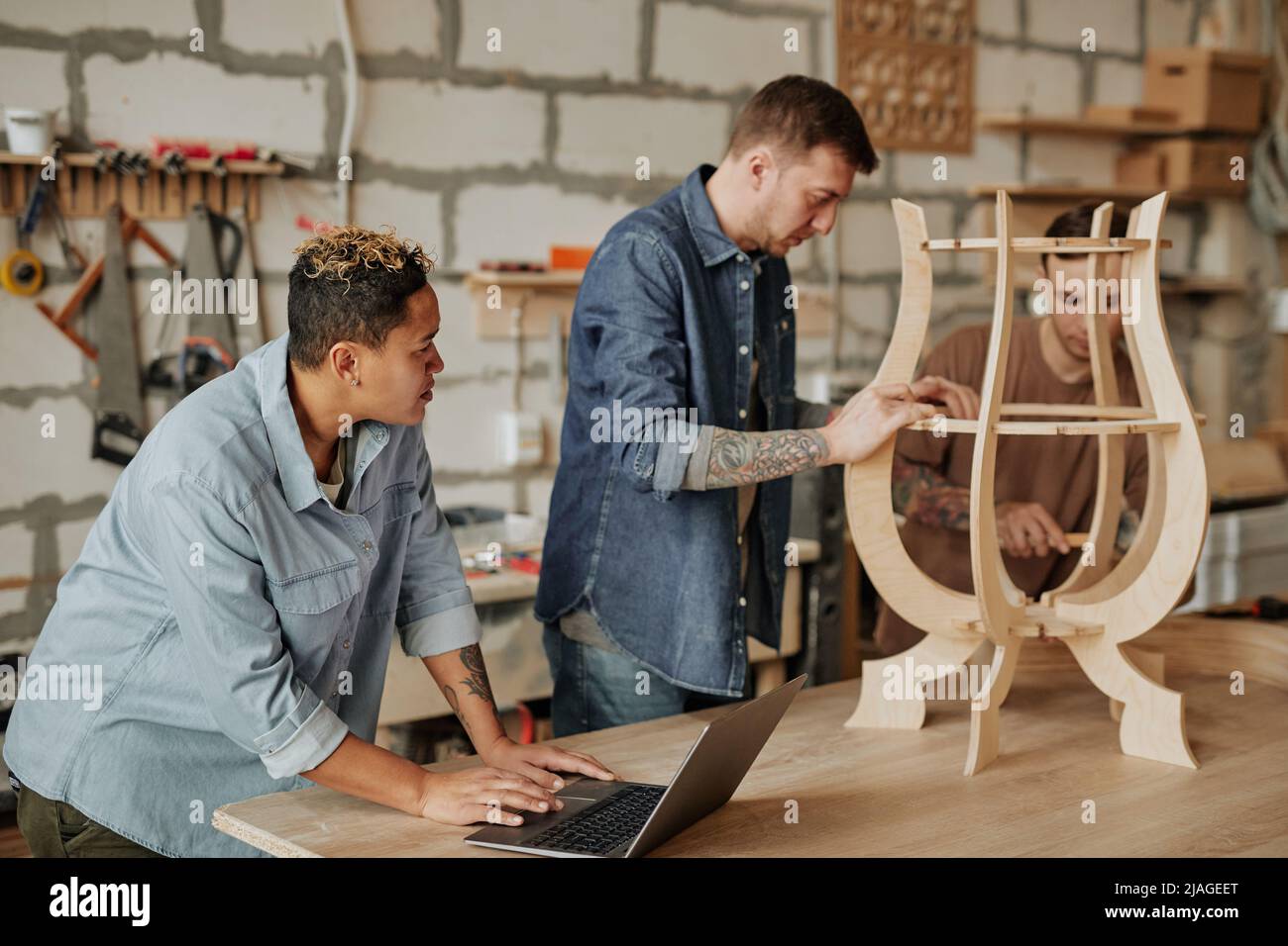 Warm toned portrait of two modern carpenters designing wooden furniture in workshop interior Stock Photo