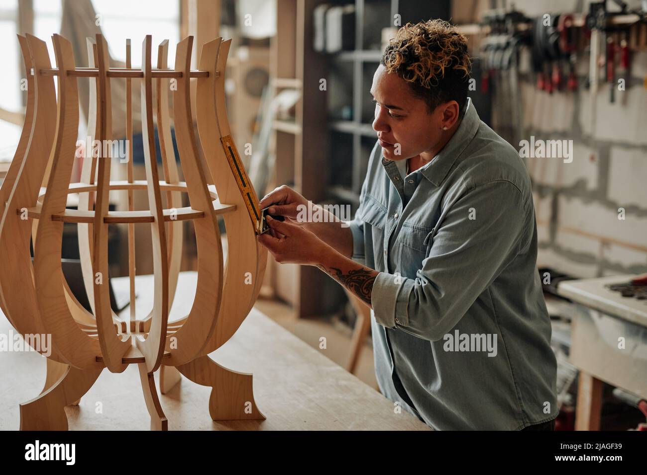 Side view portrait of modern female carpenter designing wooden furniture piece in workshop interior Stock Photo