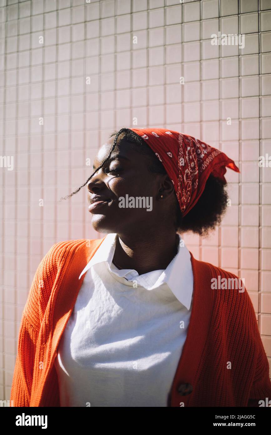 Smiling woman wearing bandana standing with eyes closed during sunny