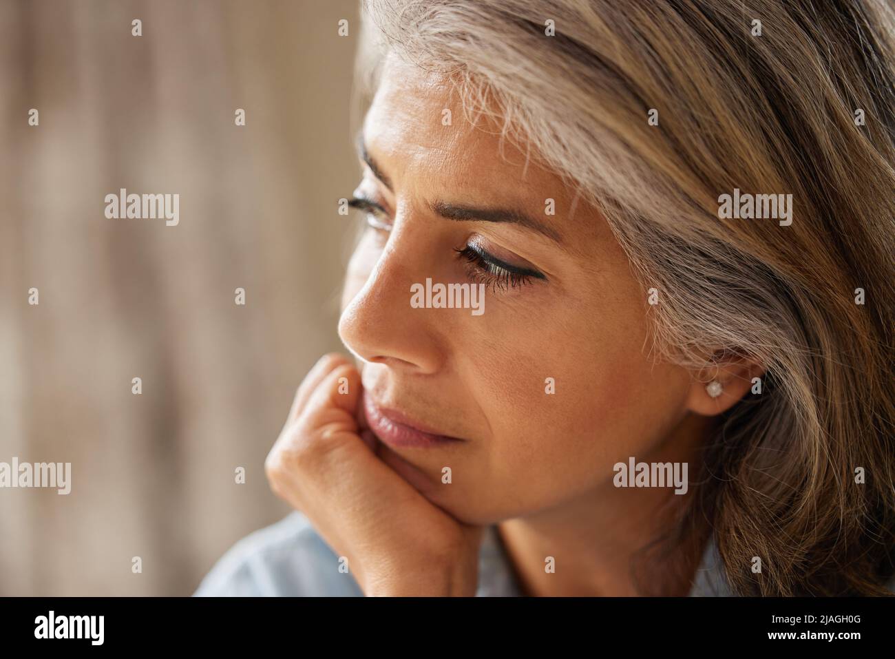 Close Up Shot Of Thoughtful Mature Woman Looking Out Of Window At Home Stock Photo