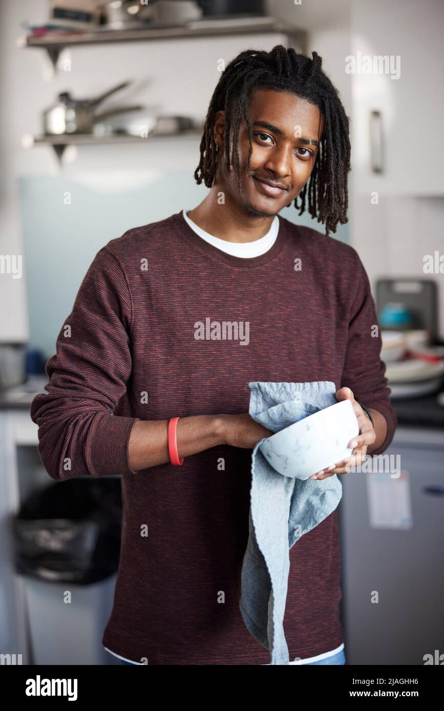 Portrait Of Male University Or College Student Drying Up Bowl l In Campus Kitchen Stock Photo