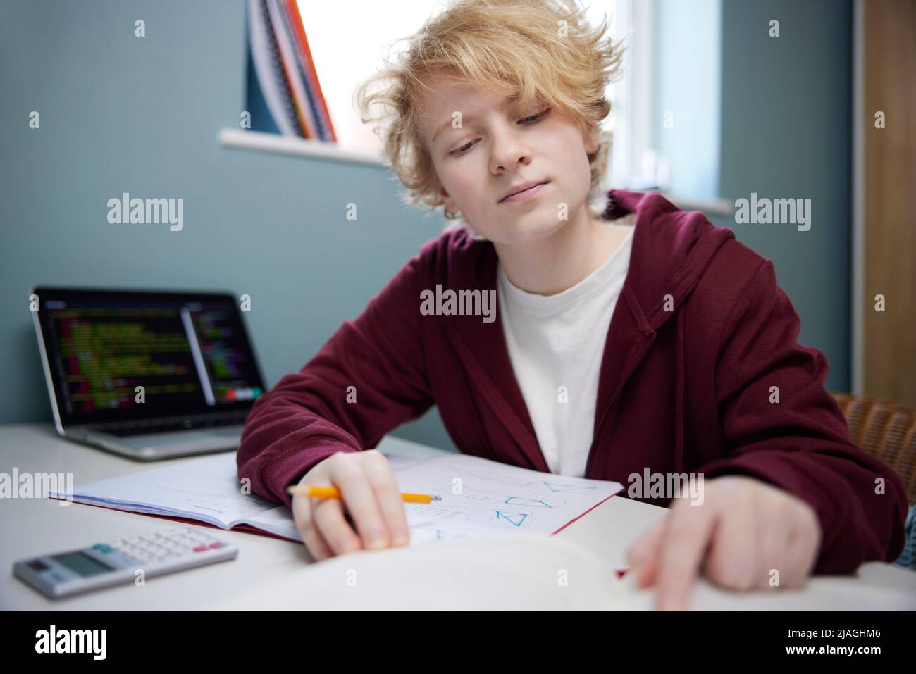 Teenage Girl Doing Homework At Desk In Bedroom Stock Photo