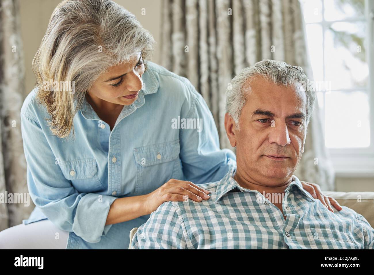 Mature Woman Comforting Man With Depression At Home Stock Photo