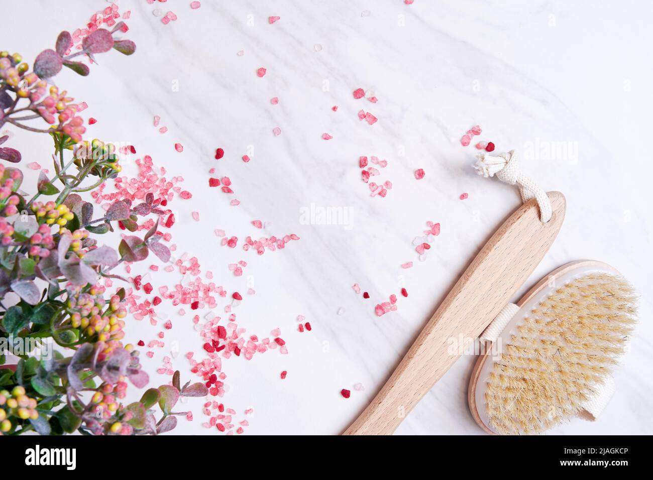 Wooden scrub brush, scented sea salt, flowers and herbs on the marble table. Spa salon backgrounds and concepts Stock Photo