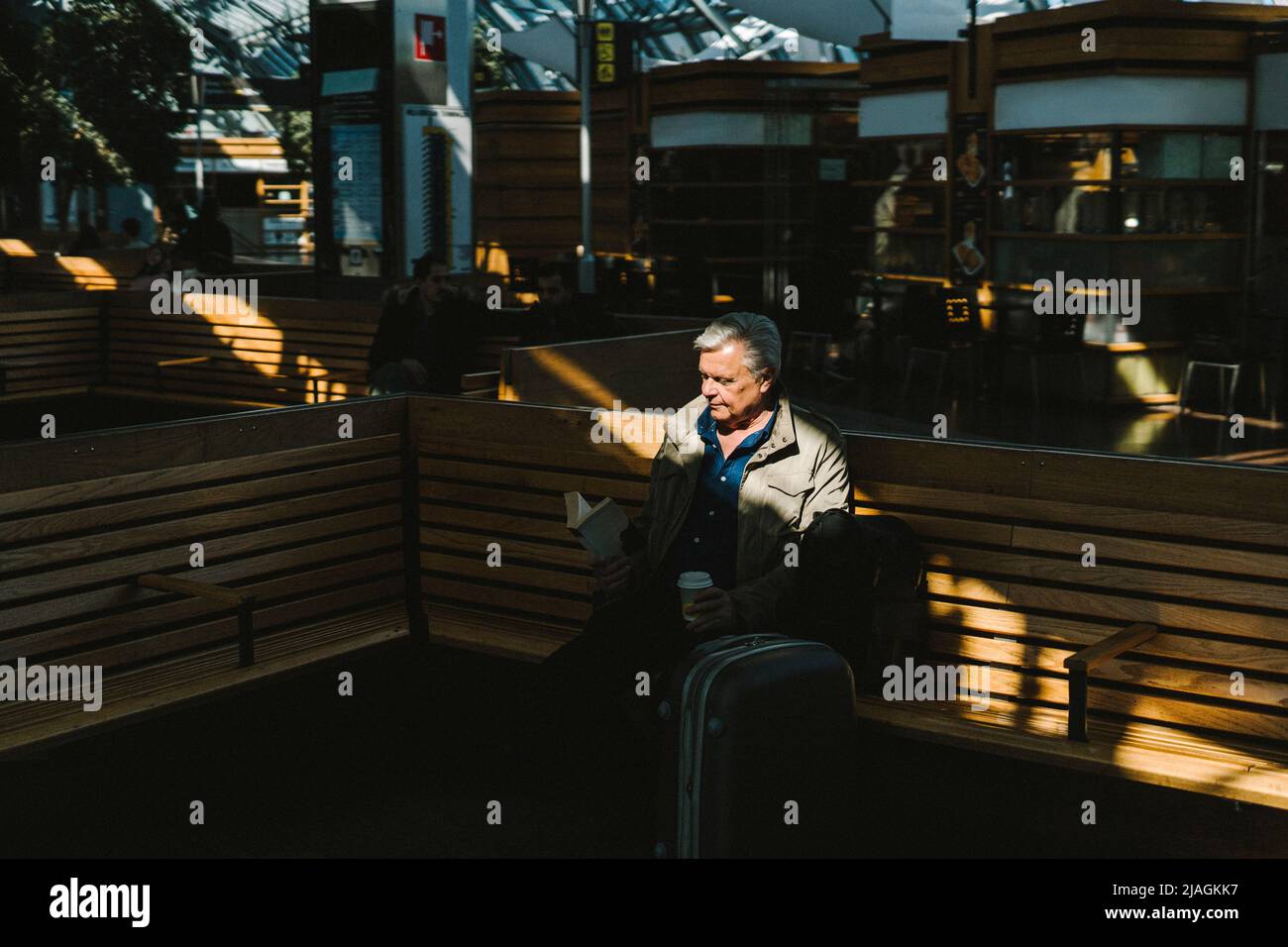 Businessman reading book while sitting on bench at railroad station Stock Photo