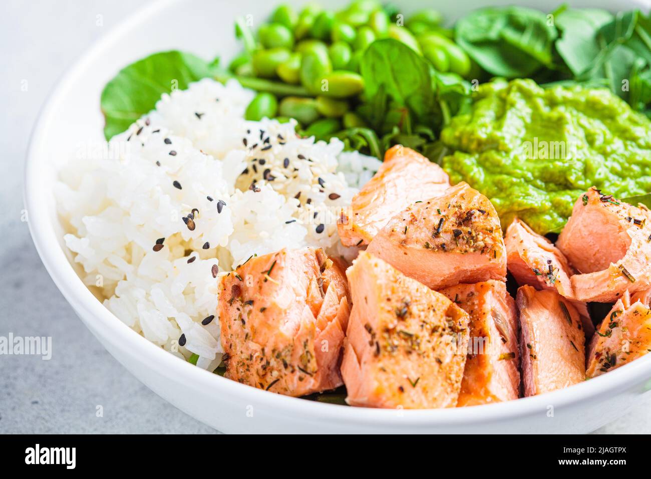 Fried salmon salad with rice, edamame and guacamole, closeup. Cooked