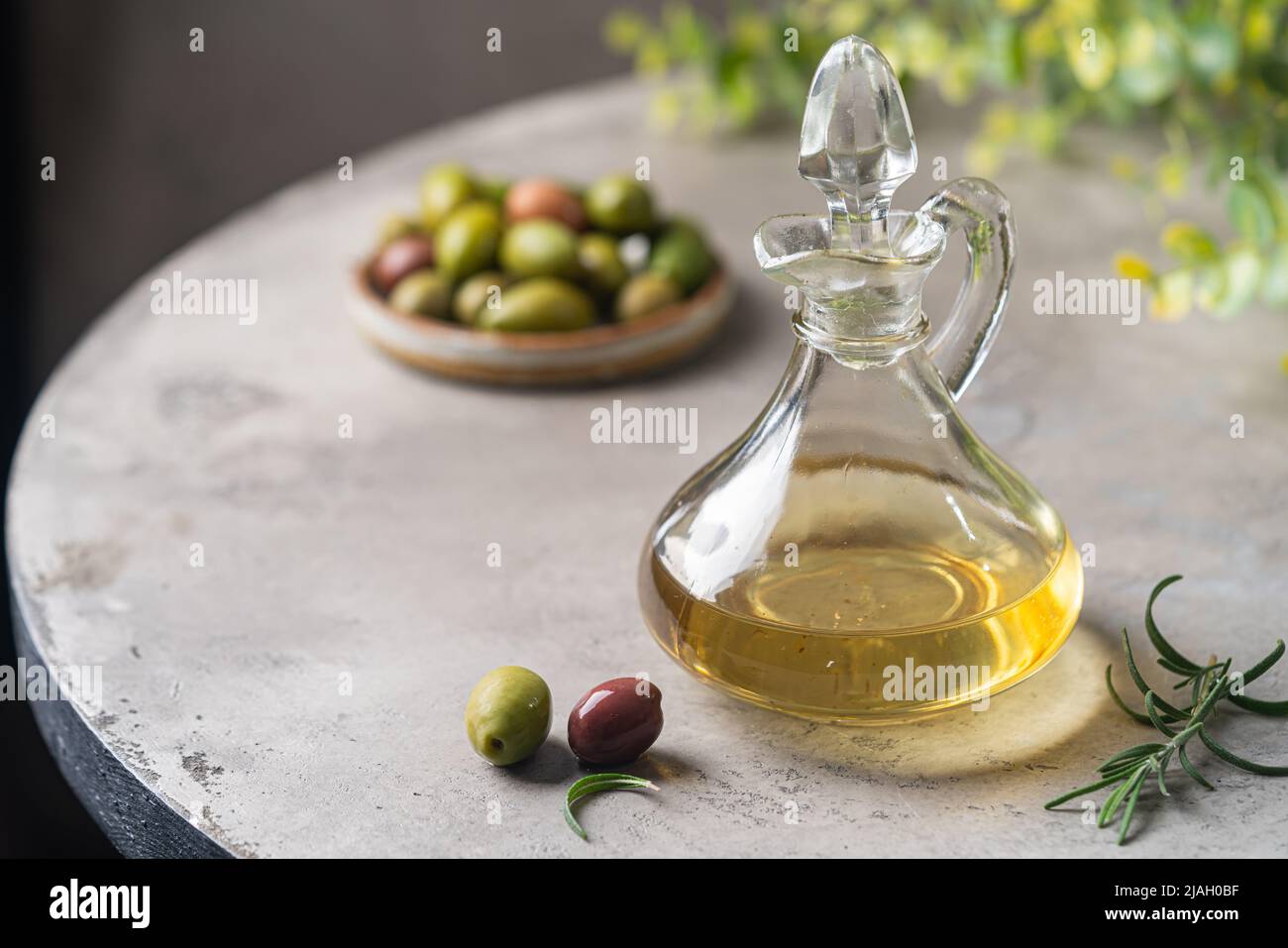 Olive oil in a glass bottle containers and harvest olives with herbs on ...