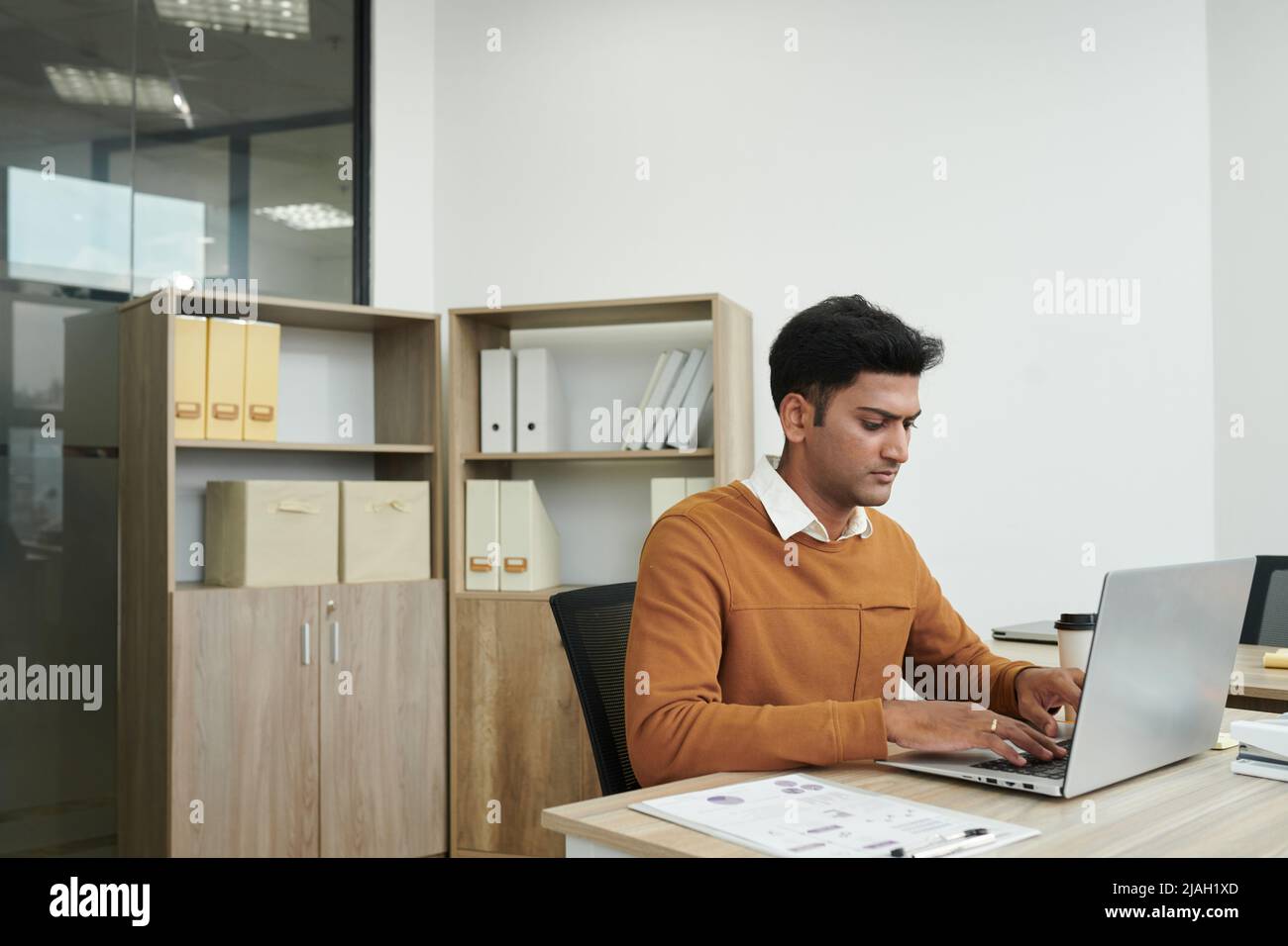 Pensive concentrated Indian entrepreneur working on laptop at office