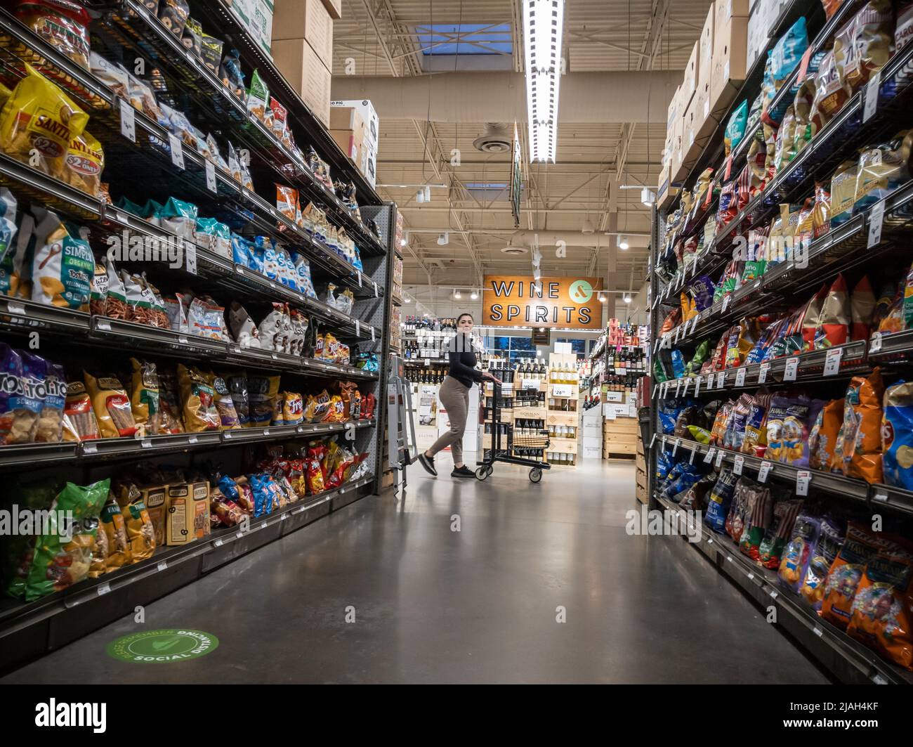 Mill Creek, WA USA - circa May 2022: View of a Hispanic woman pushing her shopping cart by the potato chip aisle inside a Town and Country grocery sto Stock Photo