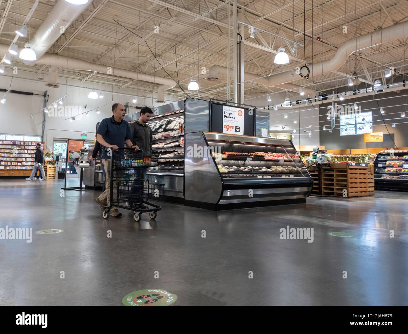 Mill Creek, WA USA - circa May 2022: Angled view of two men shopping together in the produce and meat department of a Town and Country market. Stock Photo