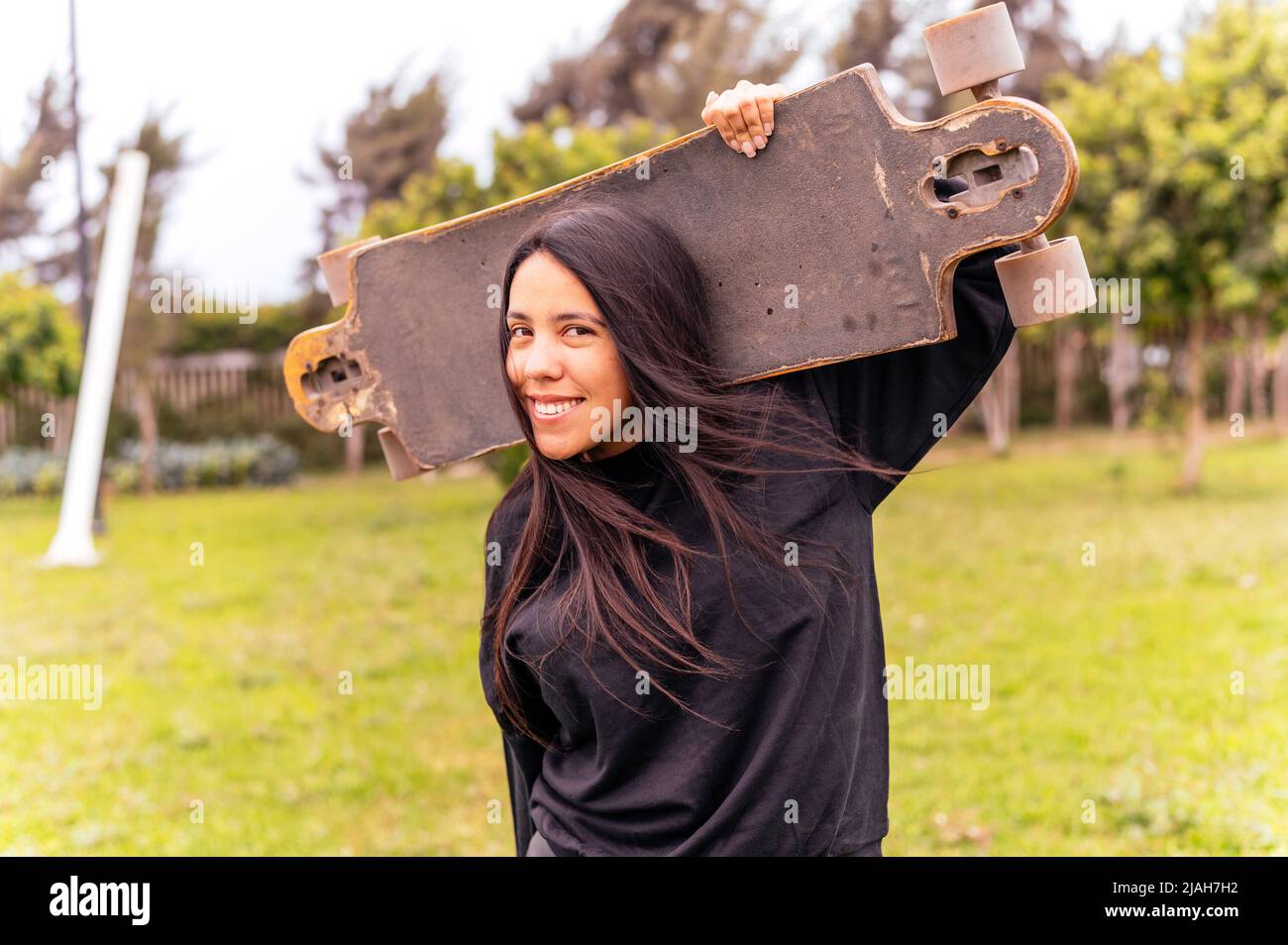 Portrait of smiling young female skateboarder holding her skateboard Stock Photo