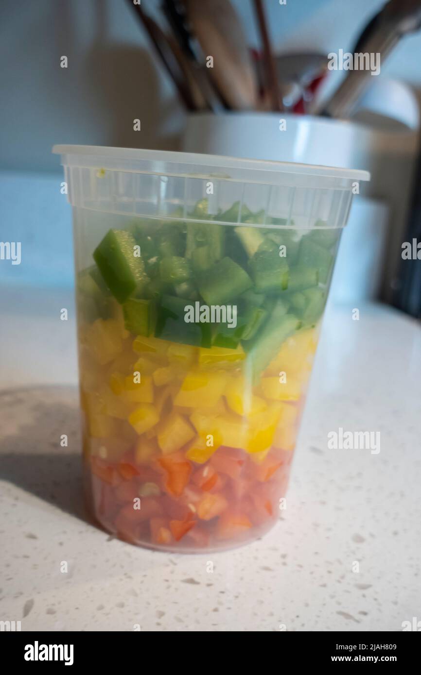 View of coloful diced bell peppers in a plastic container on a kitchen counter, prepped for cooking Stock Photo
