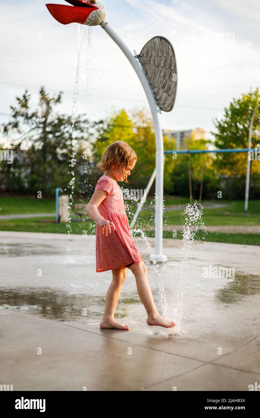 Happy child playing with water bearfoot in park splash pad. Girl at ...