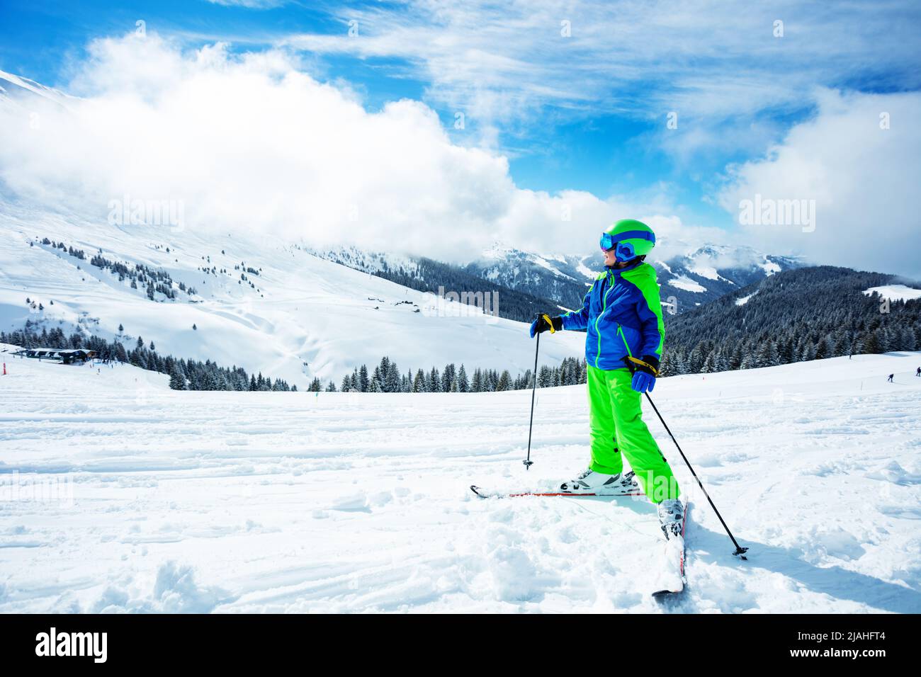 Boy stand on ski track in sport outfit observing the mountain Stock Photo