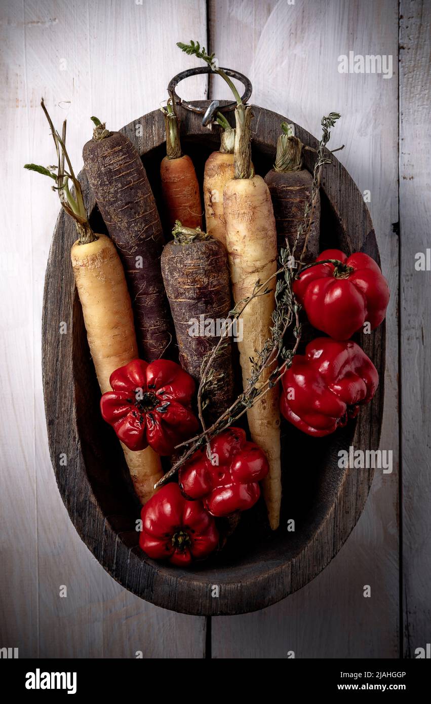 raw carrots and peppers in wooden bowl on table Stock Photo