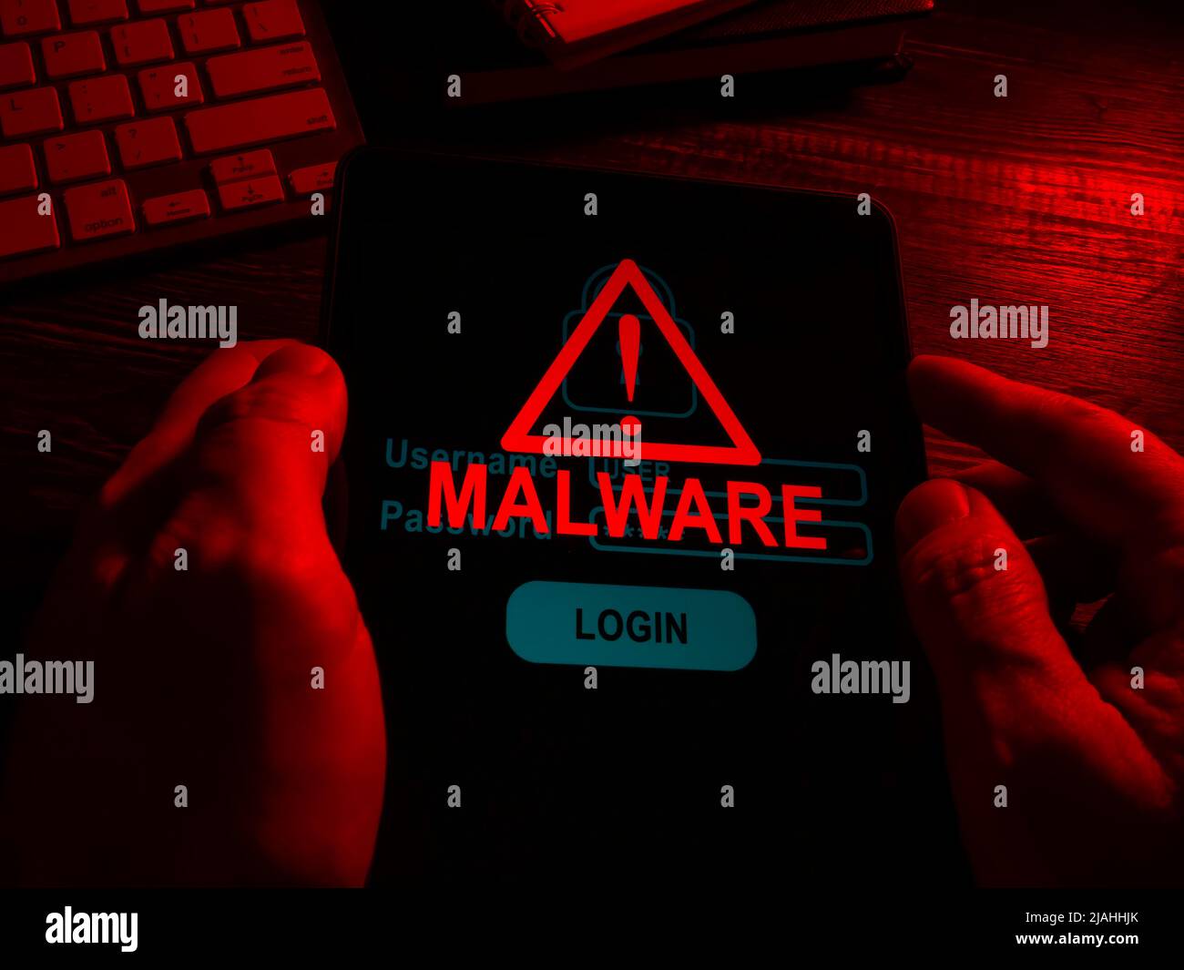 Hands in the dark hold a tablet with an inscription malware. Stock Photo