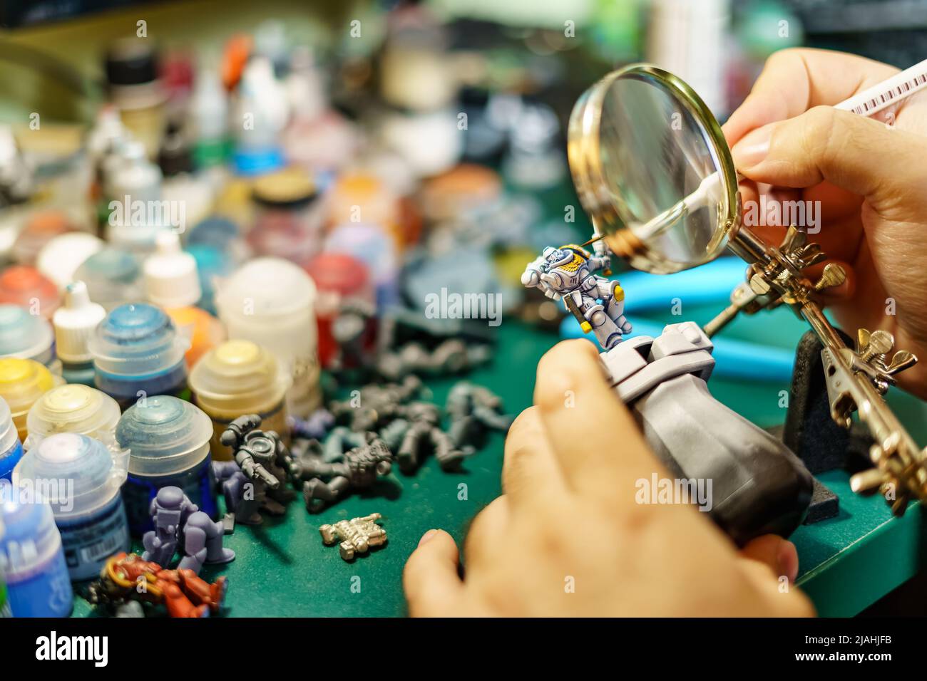 Man painting miniatures of board game with large magnifying glass Stock