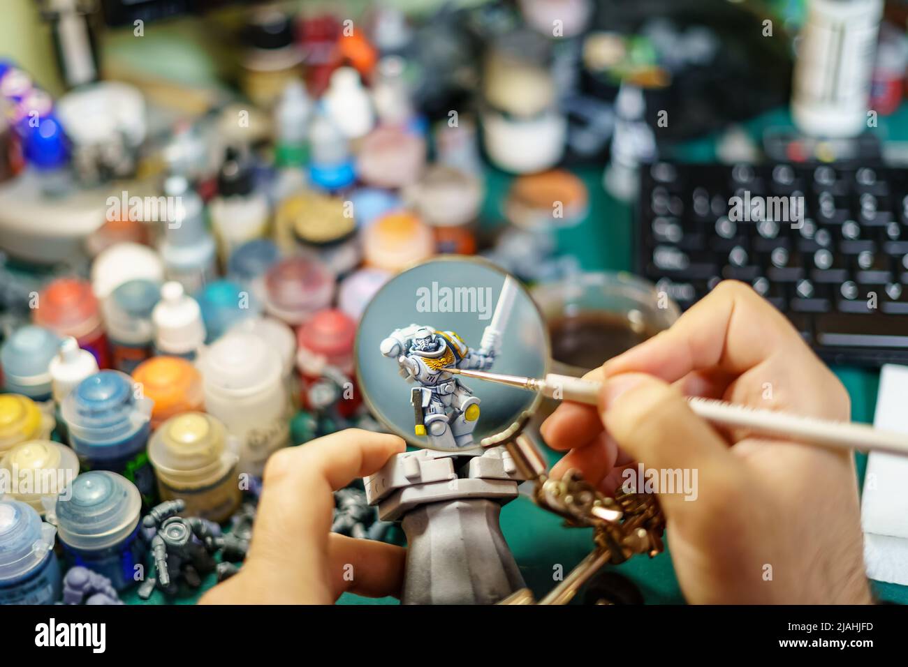 Man painting miniatures of board game with large magnifying glass Stock