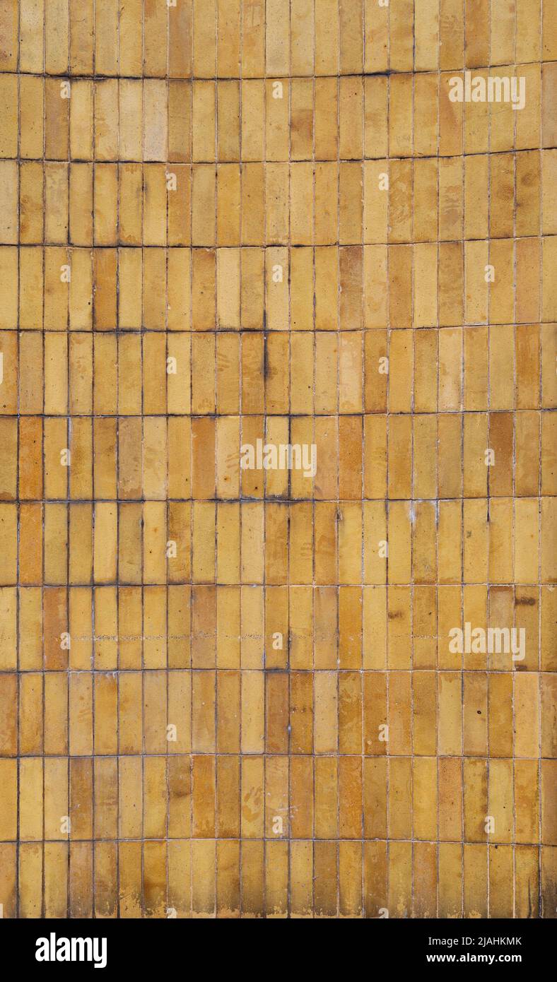 Wall made of weathered and dirty yellow and orange tiles or blocks. Front view. High resolution full frame textured background. Copy space. Stock Photo