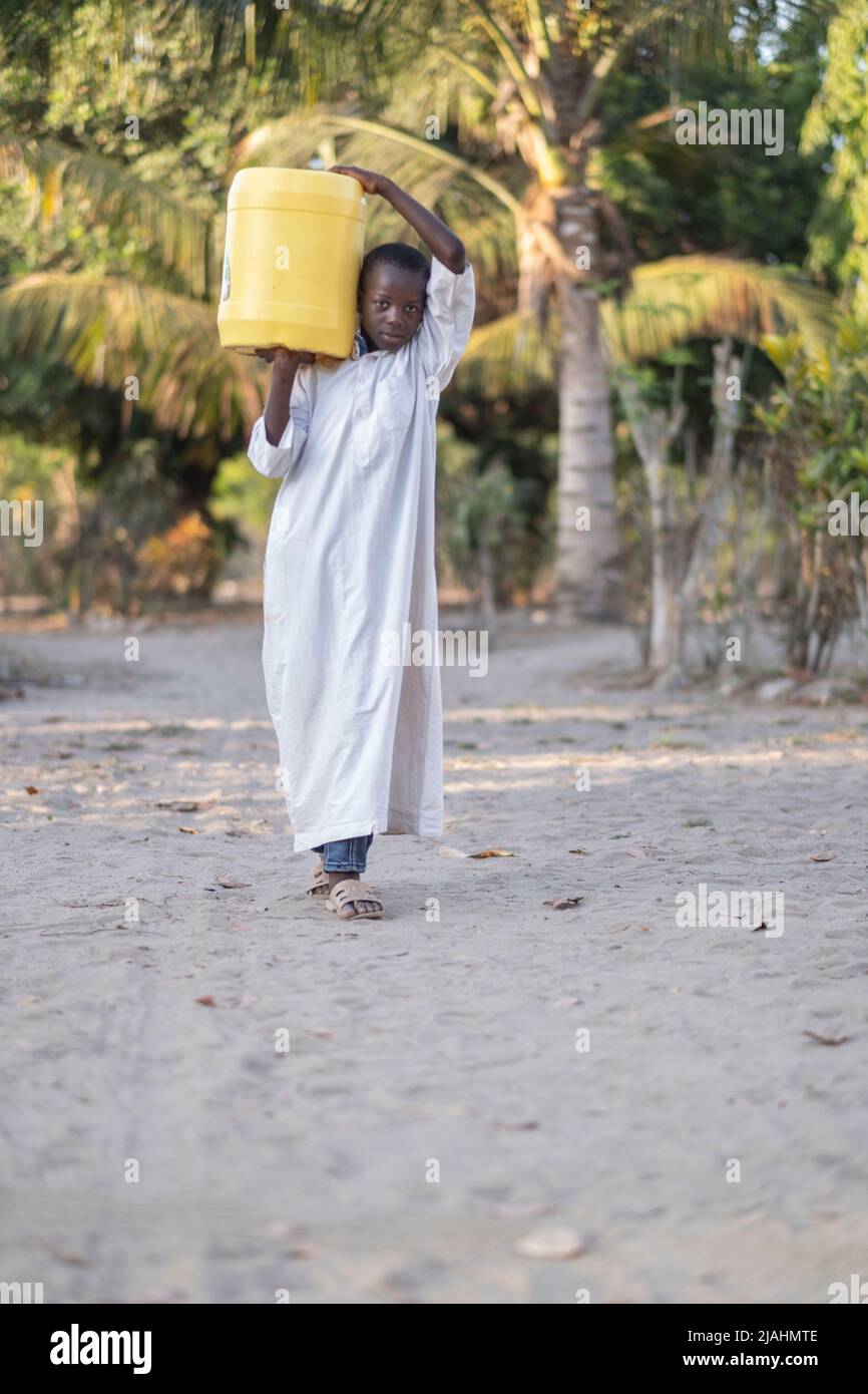 Malindi, Kenya - March 23 2021:The fight against thirst continues on the African continent. The boy carrying water to his house. Stock Photo