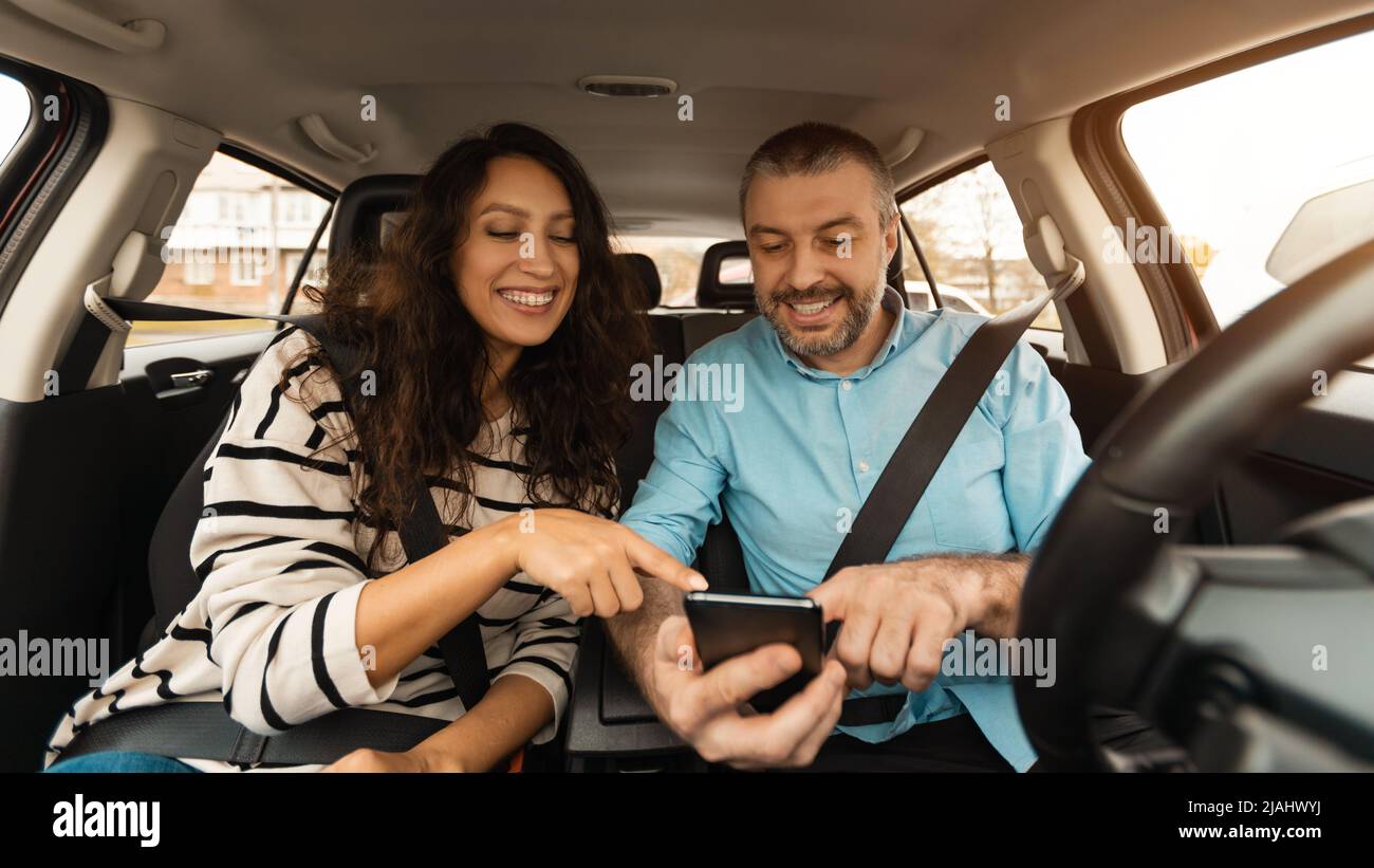 Happy couple driving car and using cell phone Stock Photo