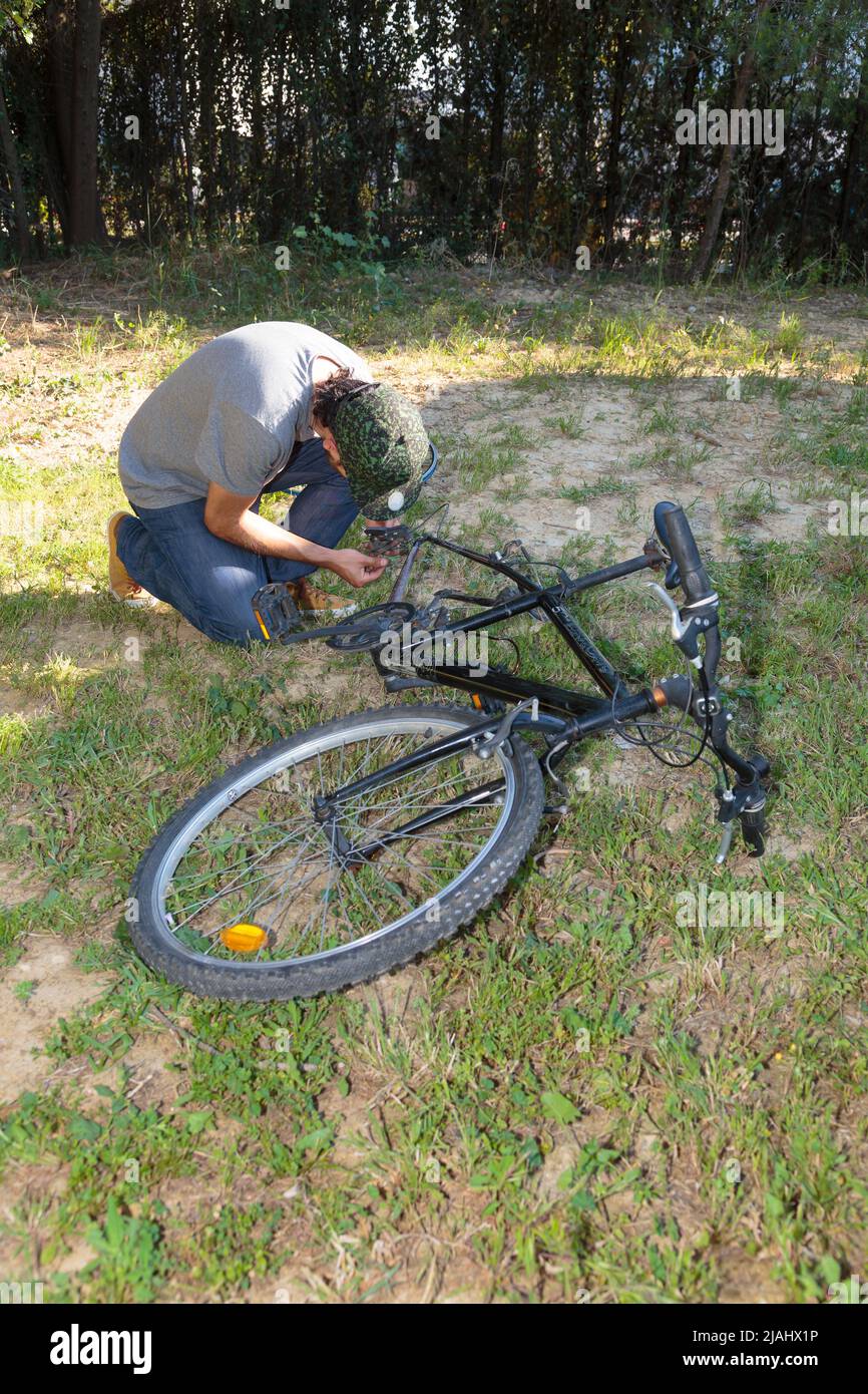 Young man repairing a bike's transmission in the backyard Stock Photo