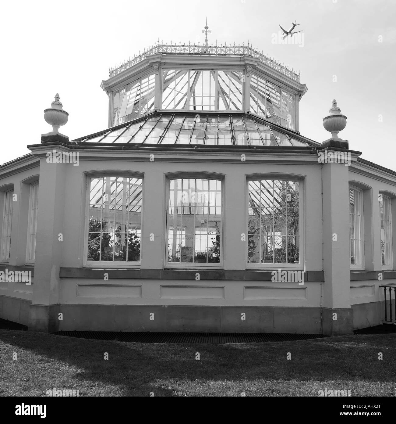 Richmond, Greater London, England, May 18 2022: Royal Botanic Gardens Kew. Temperate House with plane flying above. Monochrome. Stock Photo