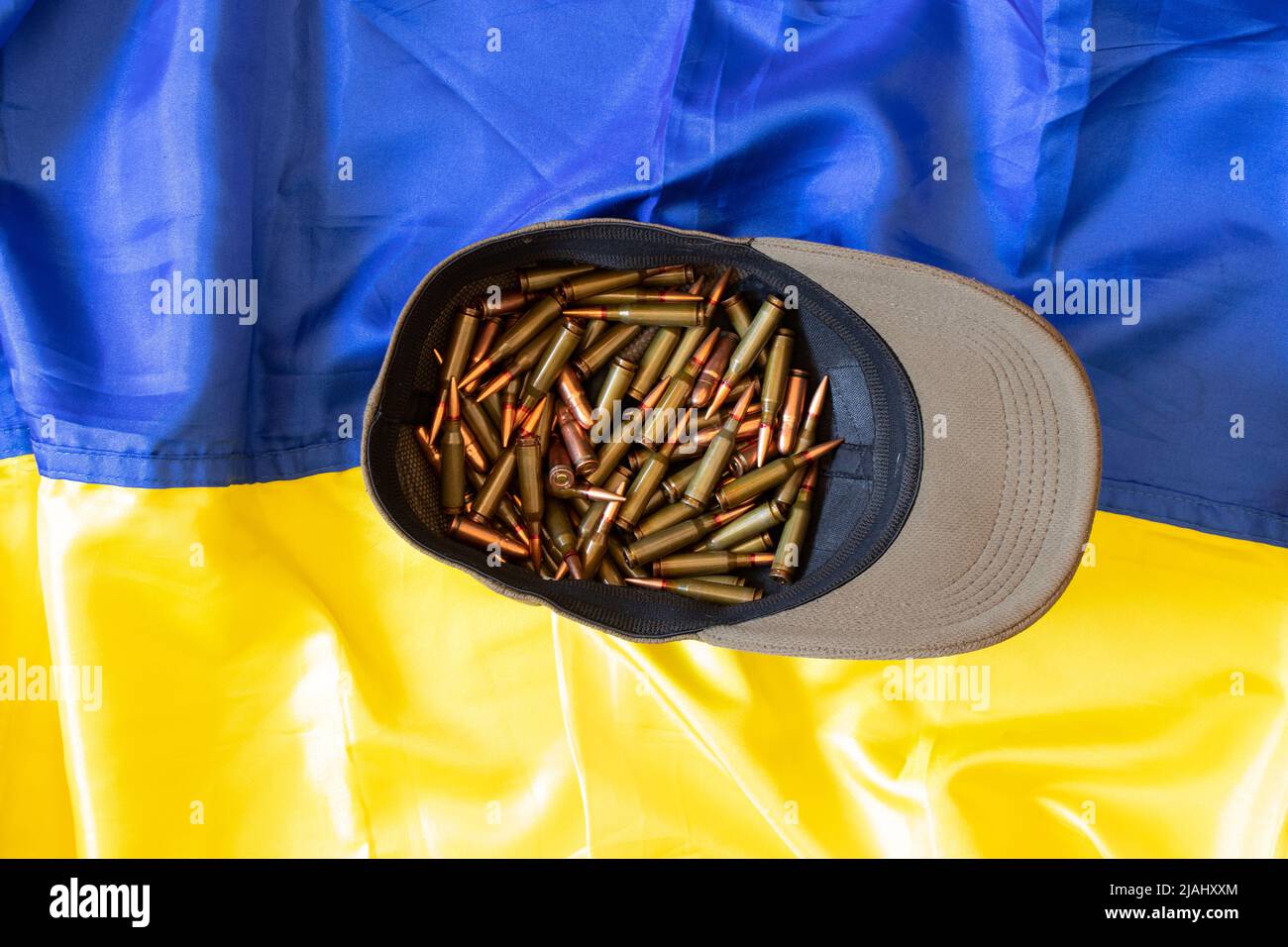 The cap of the Ukrainian soldier full of bullets lies on the flag of Ukraine, weapons, the war in Ukraine 2022 Stock Photo