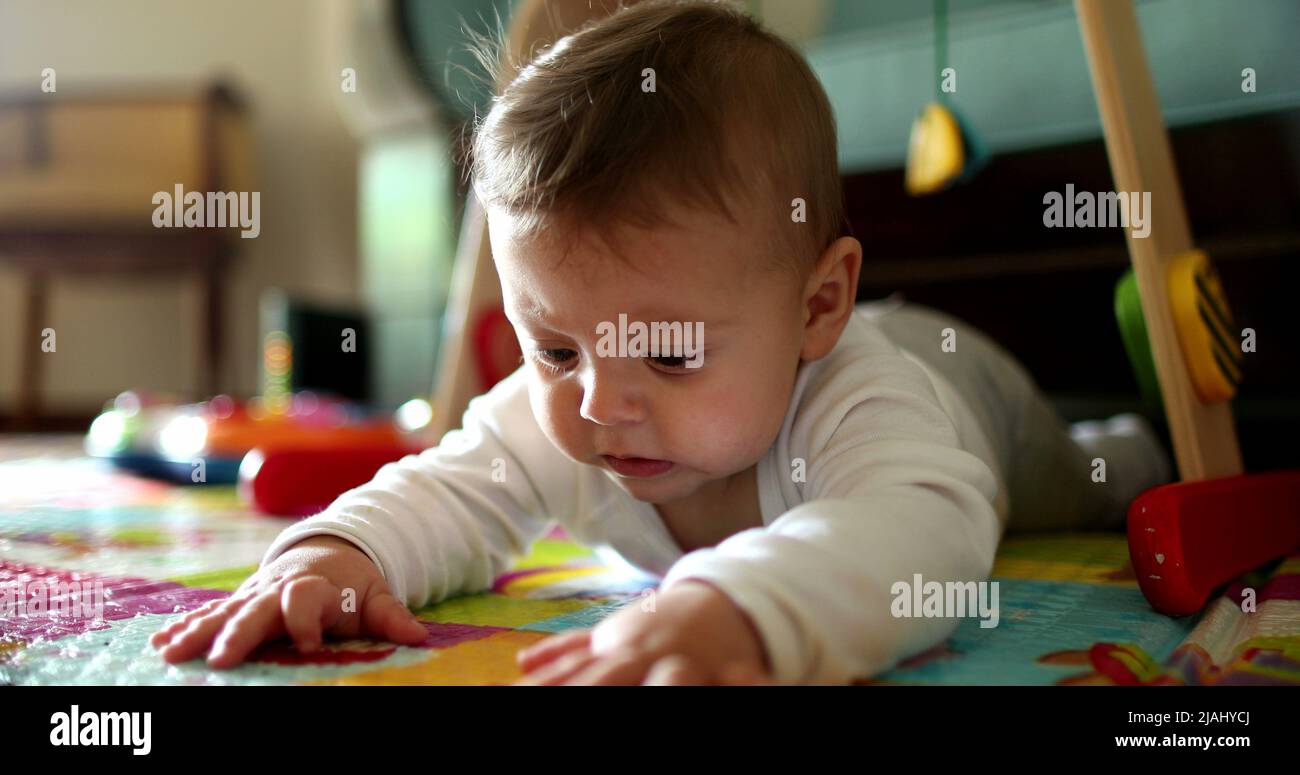 Baby infant lying on floor touching play mat, toddler discovering