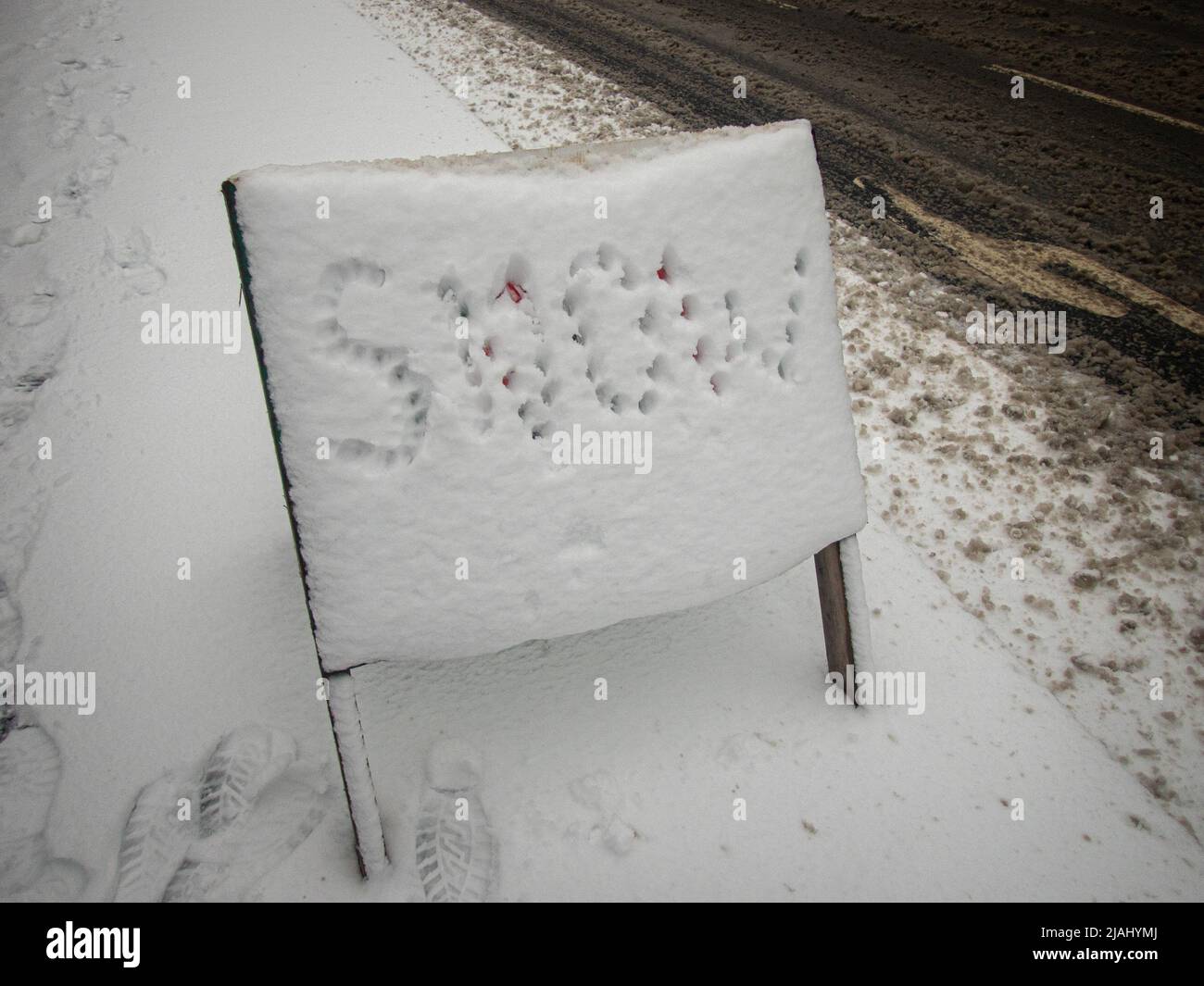 Road sign covered in snow with the word snow marked out Stock Photo