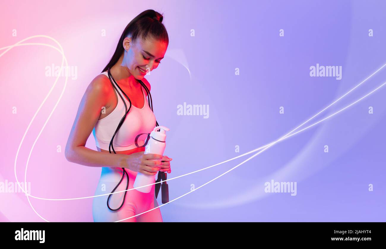 Sportswoman Holding Fitness Bottle Over Neon Background With Light Lines Stock Photo